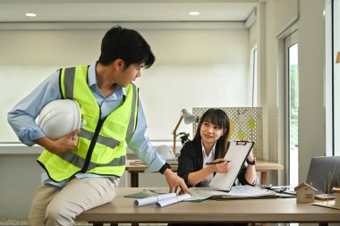Mimarlar takımı modern ofiste inşaat planlarını tartışıyor, birlikte çalışıyorlar..