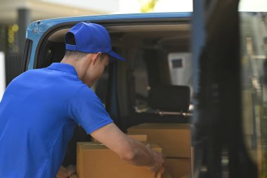 Kargo kamyonundan karton kutuları boşaltan teslimatçıların arka görüntüsü. Teslimat hizmeti, eve teslimat ve nakliye konsepti.
