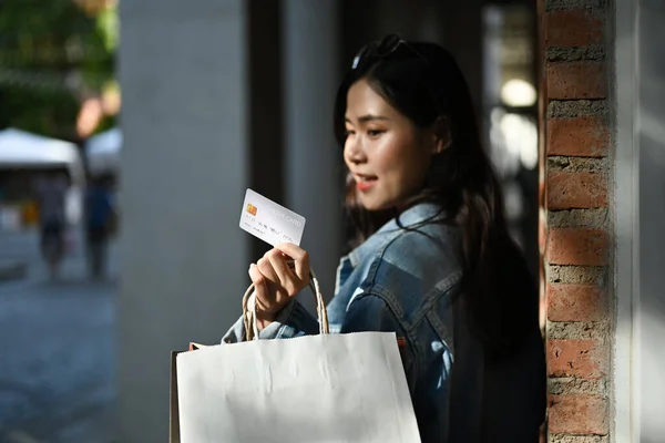 Modische Asiatische Frau Mit Einkaufstaschen Und Blick Auf Die Kreditkarte — Stockfoto