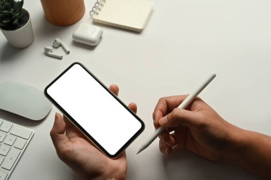 Beyaz ofis masasında cep telefonu tutan adamın yakın görüntüsü. Reklam metniniz için boş ekran.