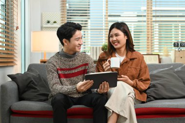 Dijital tablet kullanan mutlu Asyalı çift, kış tatillerinde birlikte vakit geçirmenin tadını çıkarıyor..