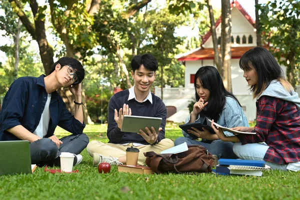 Image of university students doing group project on digital tablet while sitting in university campus. Education, Learning and community.