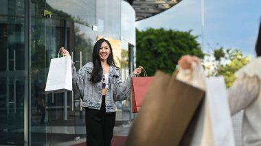 İki Asyalı genç kadının bir şehrin alışveriş bölgesinde yürürken konuşmaları, birlikte zaman geçirmeleri..