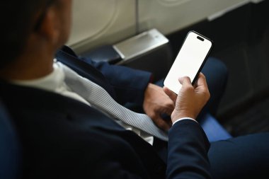 İş adamı işi kontrol ediyor, akıllı telefonda haberler, uçuş sırasında kablosuz bağlantı kullanıyor..