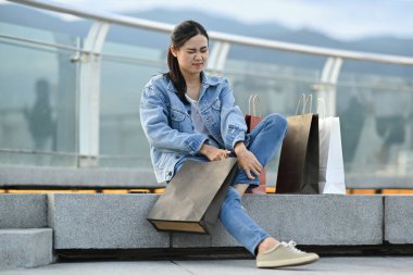 Yorgun genç bir bayan merdivenlerde dinleniyor ve bacaklarına masaj yapıyor, uzun bir günden sonra acı çekiyor..