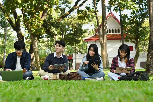 Group of students doing group project and reading book together in university campus. Education and youth lifestyle concept.