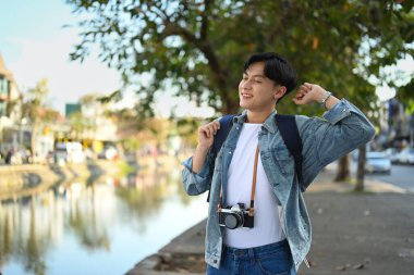 Mutlu Asyalı gezgin hippi kıyafetiyle dışarıda vakit geçiriyor, güzel bir günde sokakta yürüyor..