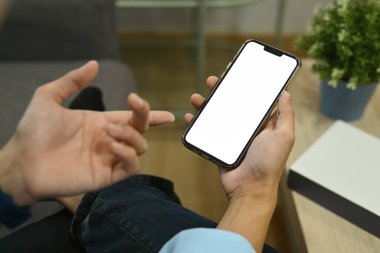 Adam rahat oturma odasında kanepede dinlenirken akıllı telefon kullanıyor. Görüntüyü kapat.