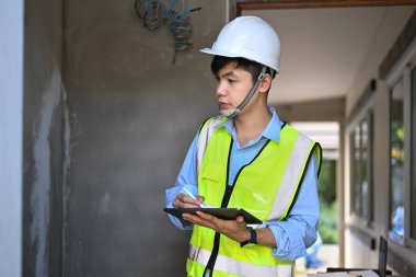 Engineer man wearing safety helmets checking building structure with checklist in hand.