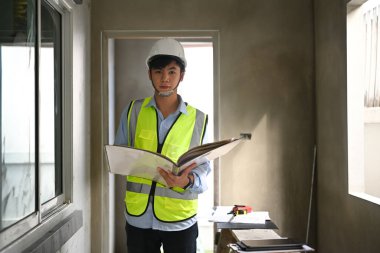 Engineer man in helmet inspecting building construction site and supervising progress of building construction project.