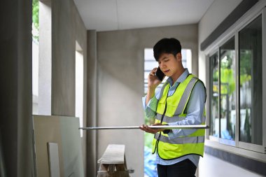 Civil engineer manager having phone conversation while standing at construction site.