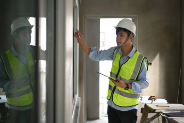 Image of civil engineer wearing hardhat working in construction site and checking schedule on his digital tablet. 