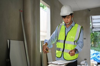 Civil engineer wearing hardhat examining plans at construction site. Engineer, construction concept.