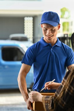 Friendly delivery man giving parcel box to customer while woman signing on digital tablet. Delivery service and shipping concept.