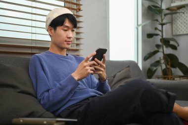 Stylish asian man shopping online, checking social media on smart phone. People and technology concept.