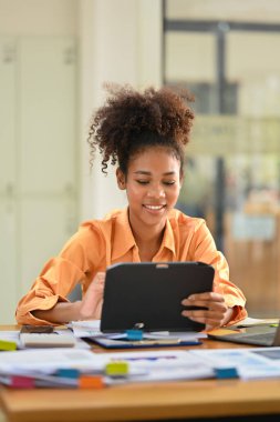 Portrait of smiling African American investor checking financial data on digital tablet.