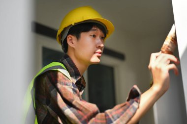 Professional painter in safety helmet holding brush in hand and paint the wall.