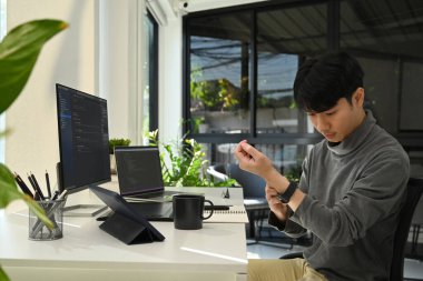 Handsome young asian man working on software development on desktop computer at modern office.