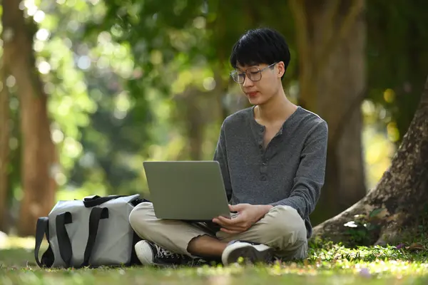 Casual Asian Man Student Using Laptop While Sitting Green Grass — Zdjęcie stockowe