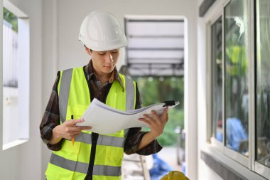 Foreman officer inspector looking at checklist paper, during perform audit at construction site.