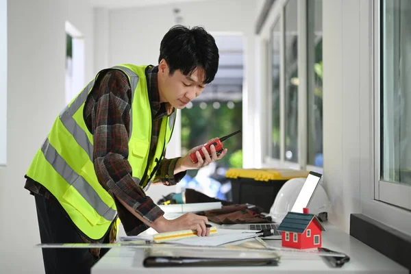 Building Inspector, engineer holding walkie talkie and working at construction site.