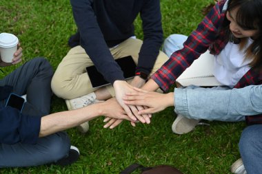 Above view of university friends stacking hands together, showing unity and togetherness. Youth lifestyle and friendship concept. 