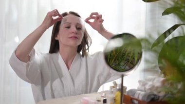 Young woman is removing facial moisturising mask from face,doing her everyday routine. Beauty and self care concept.