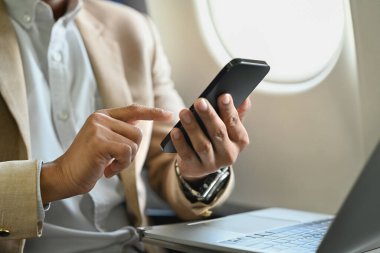 Businessman passenger working on laptop and typing text on mobile phone using wireless connection on board.