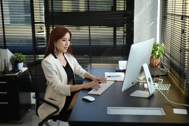 Professional businesswoman looking at computer screen, comparing corporate income for previous year with current one.