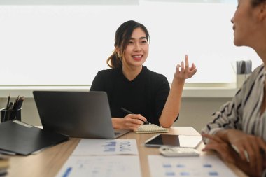 Confident asian woman manager explaining new strategies to coworkers during meeting in office.