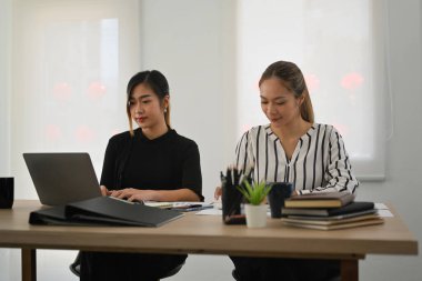 Two focused female employee preparing presentation for company clients or investors at office.
