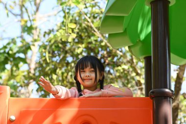 Cute preschooler asian girl having fun on outdoor playground. Childhood and equipment of entertainment park for kids.