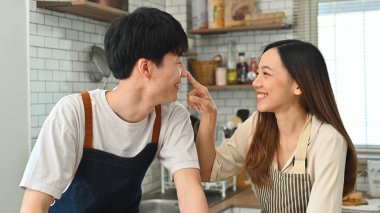 Happy young couple having fun cooking together in kitchen, spending leisure weekend at home together. Romantic moment. 