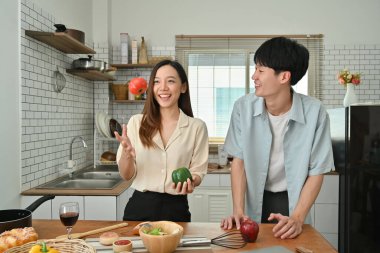 Adorable young couple enjoying spending time together while cooking in modern kitchen.