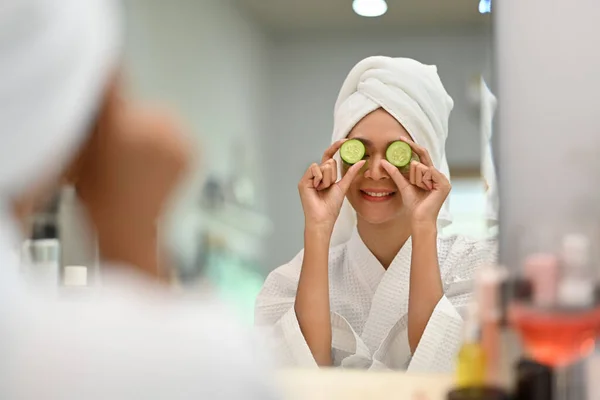 Playful Young Woman Bathrobe Holding Slices Fresh Cucumber Taking Spa — стоковое фото