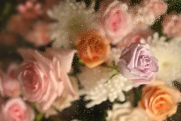 Cold foggy glass with beautiful pink roses and white chrysanthemums inside with dripping water drops, for floral botanical wallpaper.