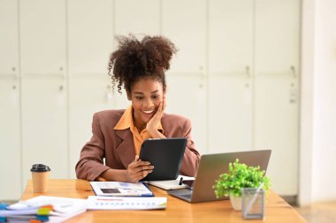 Smiling female financial advisor using tablet for checking information or chatting online with her client.