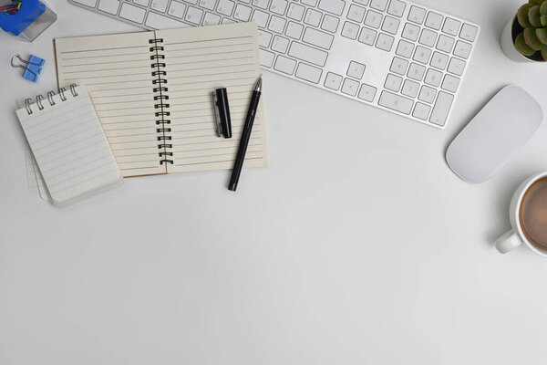 Top view of blank notepad, cup of coffee, wireless headphone and mouse on white table. Copy space for your text.