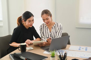 Dizüstü bilgisayar kullanan ve şirket müşterileri veya yatırımcıları için sunum hazırlayan çok ırklı kadın meslektaşlar.