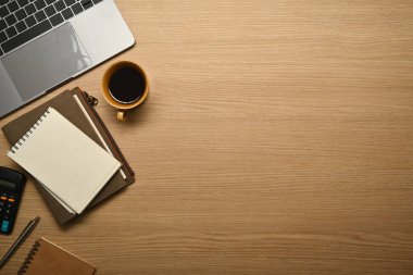 Simple workplace with laptop computer, notepad, coffee cup and calculator on wooden table. Top view copy space.