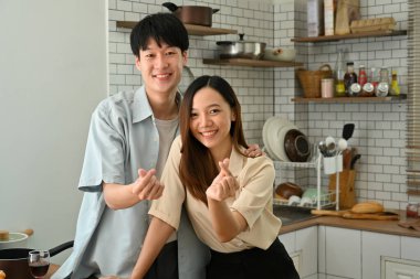Image of beautiful young married couple showing heart with fingers gesture mini love and smiling to camera.