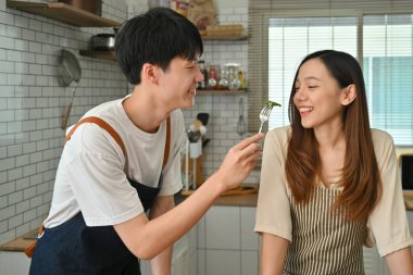 Romantic young couple eating vegetable vegetarian salad together in the kitchen. Family moments, healthy lifestyle concept.