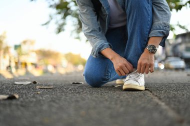 Cropped image of hipster man traveller tying shoe laces for city walk.