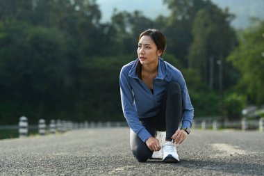 Image of asian woman tying shoelace before running outdoors. Fitness, sport and healthy lifestyle concept.