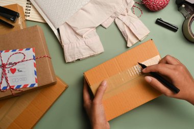Top view, above view of man writing address on carton box, seller preparing parcel box of product for shipping.
