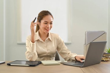 Charming asian female manager watching online webinar on computer, sitting at modern office.