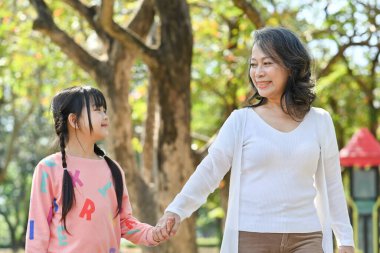 Happy middle aged woman and little granddaughter enjoying leisure weekend tine at outdoor.