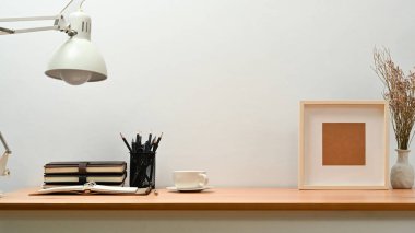 Interior of home office with books, pencil holder and picture frame on wooden table. Copy space for your text.