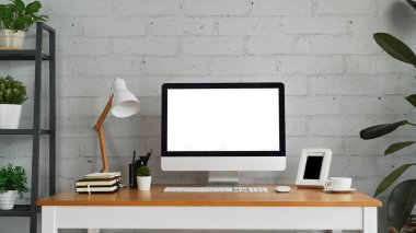 Front view of blank computer screen, lamp and supplies on wooden desk. Empty screen for your advertising and creative design.