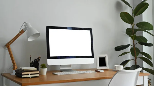 Modern workplace with blank computer screen, lamp and supplies on wooden desk. Empty screen for your advertising design.